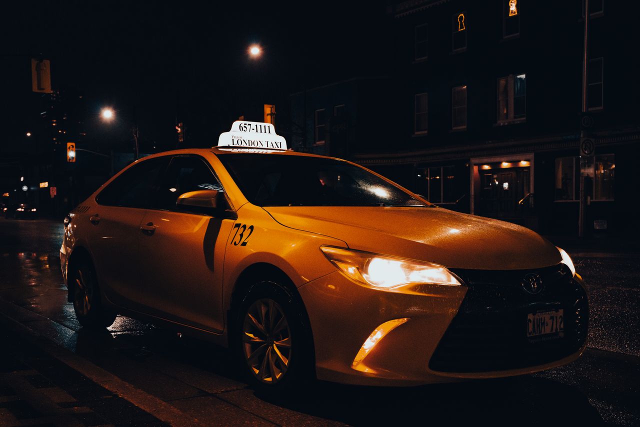 services-02 A yellow taxi waiting at night in London, Ontario, Canada. Urban transportation captured with street lights.