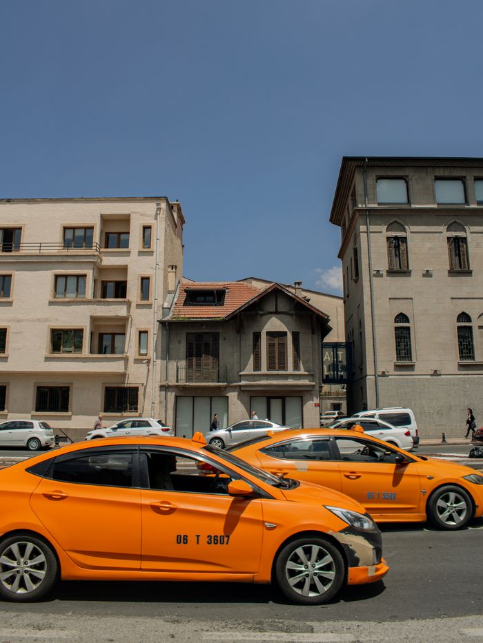 gallery-4 Street view of yellow taxis in front of historic buildings under clear blue sky.