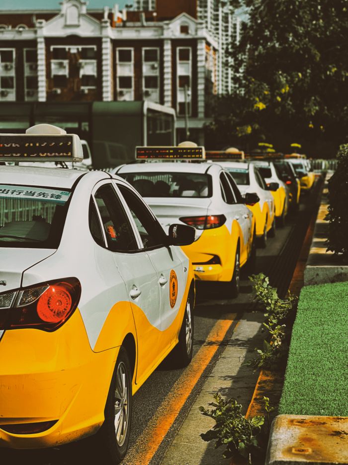 contact-img A row of yellow taxi cabs waits on a city street, providing urban transportation.