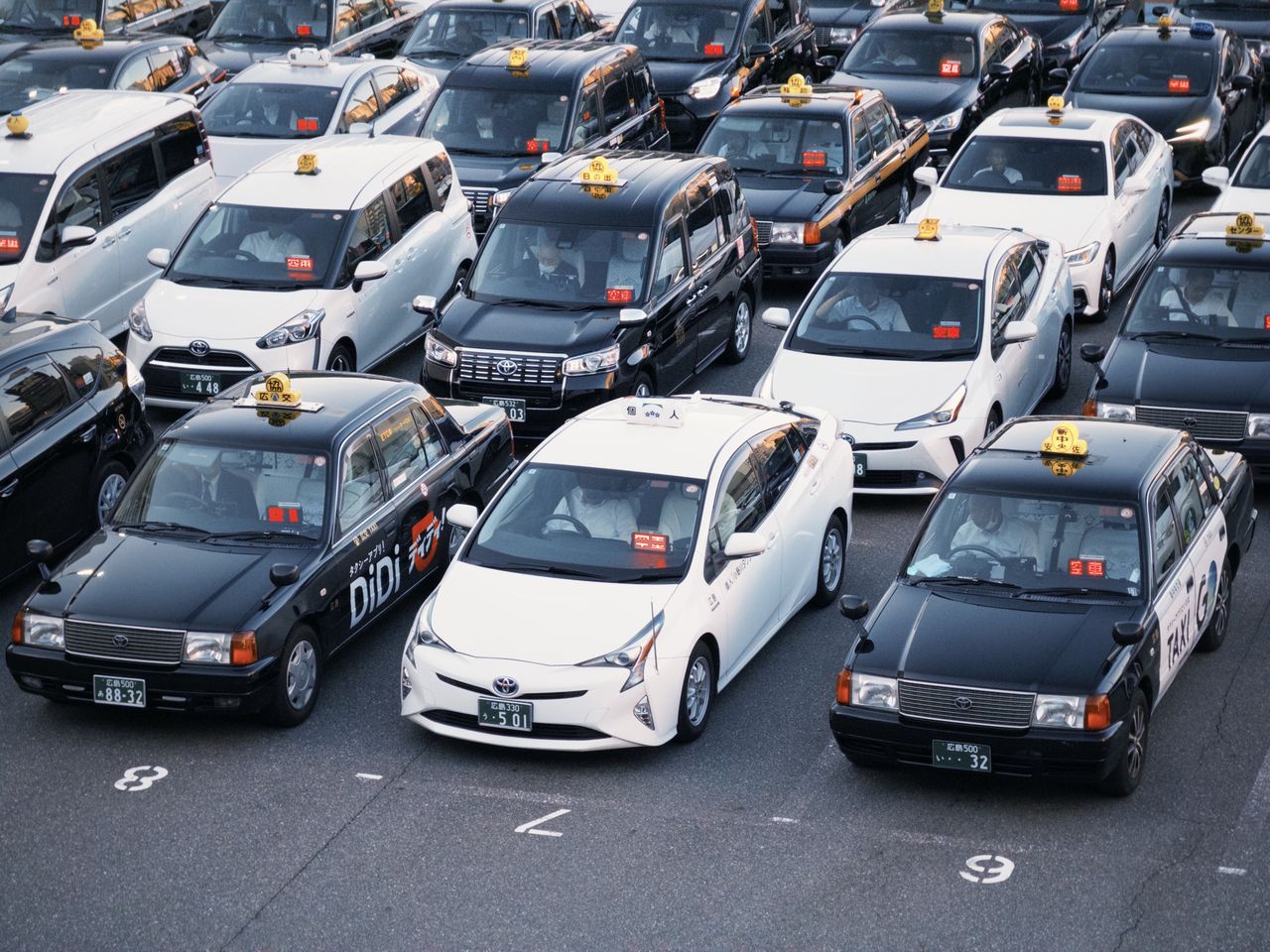 services-04 Taxis lined up in a parking lot, showcasing urban transportation in Japan.